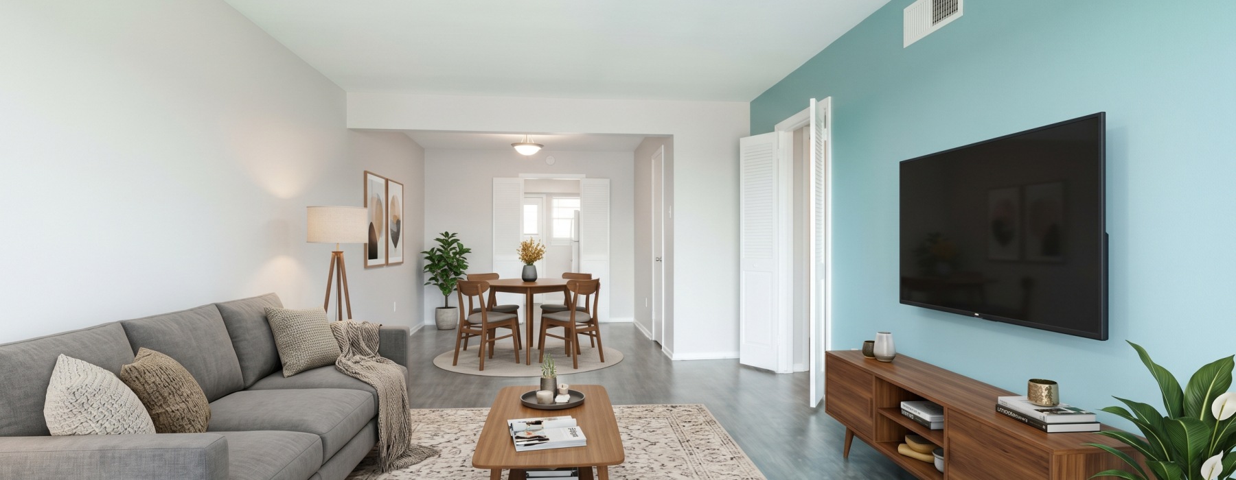 open living space with a couch, tv, blue wall, grey wood flooring, and beige rug